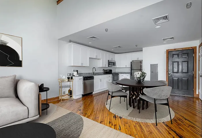 Apartments Near Lehigh Valley Zoo in Allentown, PA - The Mill - Living Room with a Large Grey Sofa, a Ceiling Fan, and Oversized Windows Allowing Natural Light