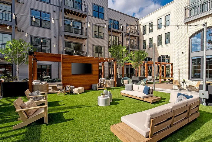 Elegant outdoor courtyard with modern seating, lush greenery, and ambient lighting.