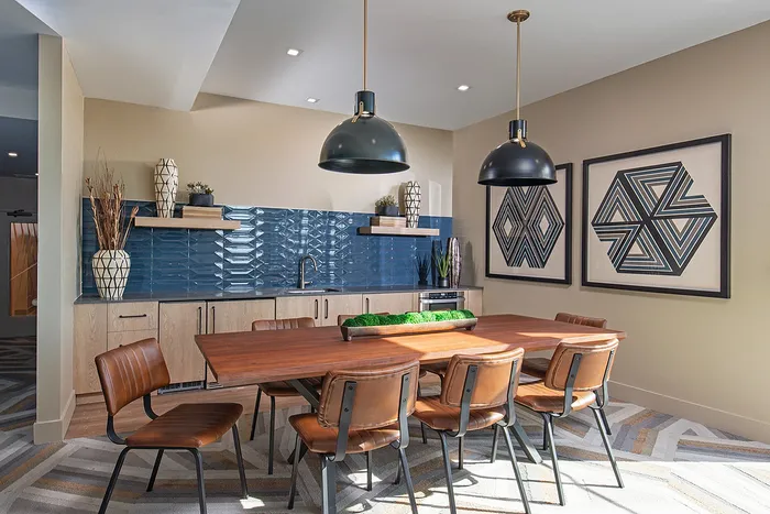 Contemporary dining room with a stylish wooden table, leather chairs, and modern kitchen decor.