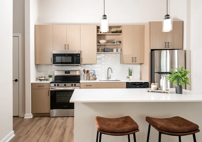 Modern kitchen with light wood cabinets, stainless steel appliances, and a spacious island with bar stools.