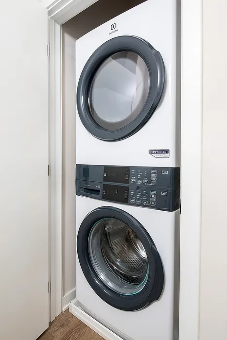 Compact laundry setup with a modern stacked washer and dryer unit in a cozy alcove.
