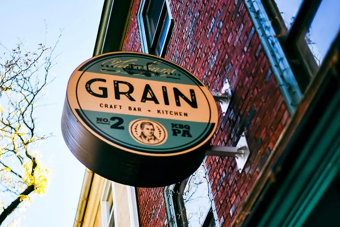 Inviting round sign for Grain Craft Bar and Kitchen on a brick building facade.