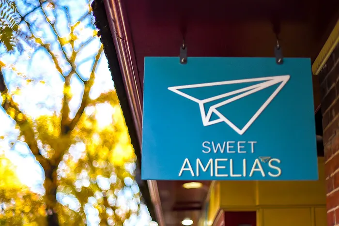 Colorful bakery sign with a paper airplane graphic and 'Sweet Amelia's' text.