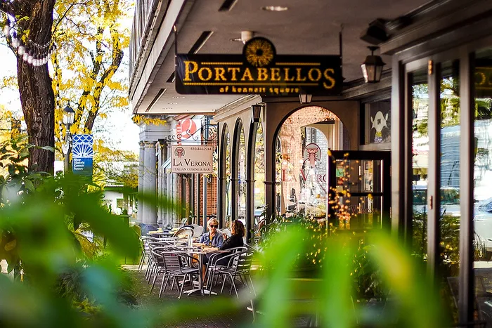 Cozy outdoor seating at an inviting cafe with lush greenery and stylish decor.