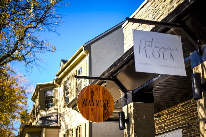 Inviting exterior featuring boutique signs of Wayvine and Patisserie Lola against a bright, clear sky.