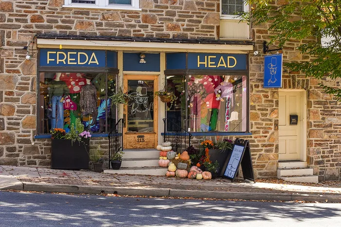 Inviting stone facade of Freda Head boutique with colorful window displays and seasonal decorations.