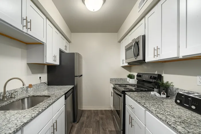 Modern kitchen with stainless steel appliances, granite countertops, and white cabinetry.