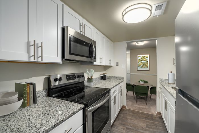 Contemporary kitchen with sleek granite countertops, stainless steel appliances, and a view into a cozy dining nook.