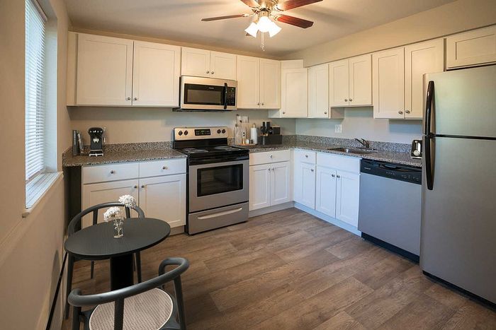 Charming kitchen with modern appliances, granite countertops, and white cabinetry.