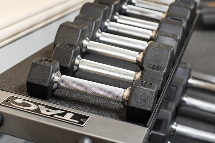 Close-up of a sleek dumbbell set neatly arranged on a rack in a modern fitness center.