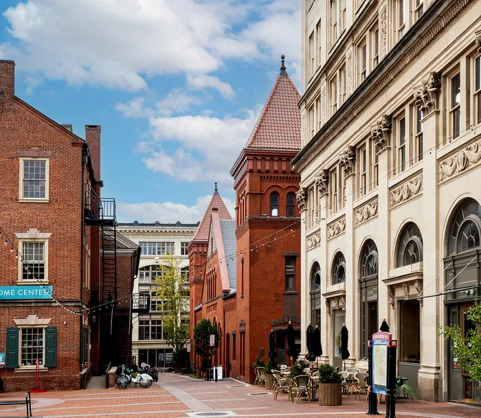 Scenic view of a vibrant urban street with historic brick buildings and outdoor cafe seating.