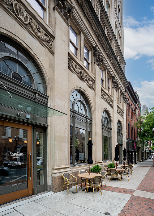 Charming street view featuring a historic building with ornate stonework and outdoor seating.