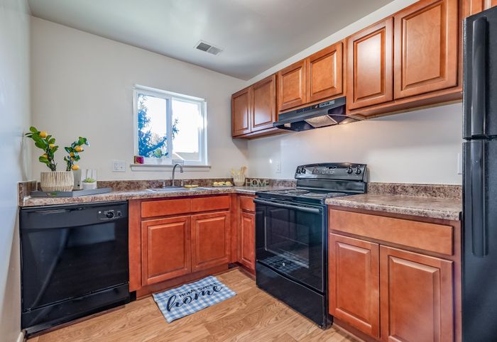 Inviting kitchen with wooden cabinets, modern appliances, and a cozy window view.