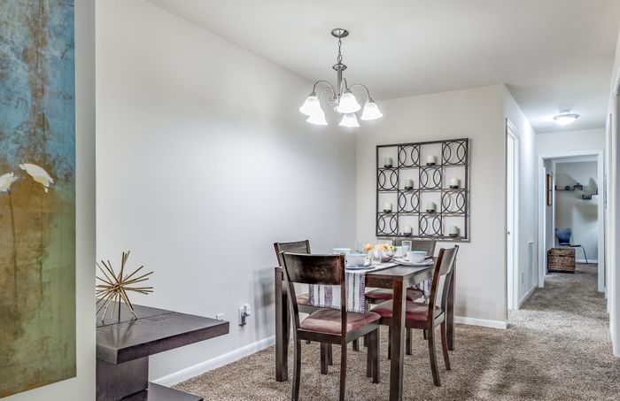 Chic dining setup in a modern apartment with a stylish chandelier and contemporary wall art.