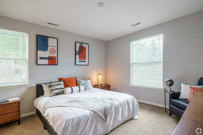 Inviting bedroom with modern artwork, plush bedding, and natural light through wide windows.