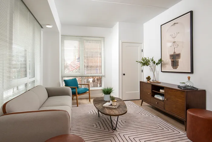 Pet-Friendly Apartments In Lancaster, PA - 202 Queen Apartments - Living Room With Wood-Style Flooring, Area Rug, Couch, Armchair, Coffee Table, Oversized Windows, And Direct Access To The Kitchen