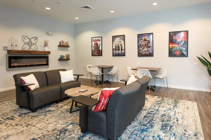 Resident apartment lounge with seating areas and an entryway to the kitchen and outdoor pool.