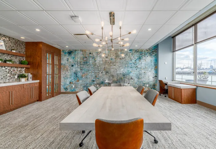Elegant meeting room with modern chandelier, abstract wall art, and large window offering a scenic view.