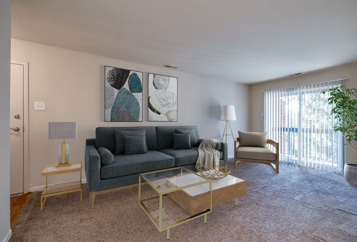 Bright and inviting living room with plush carpet, chic green sofa, and stylish decor, featuring large artwork and natural light through wide windows.