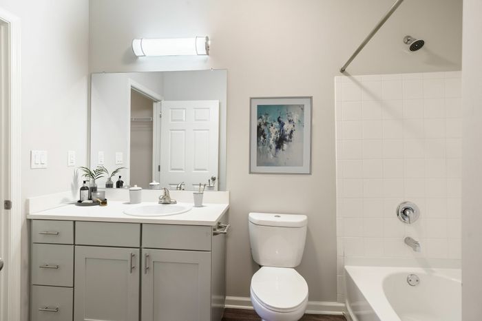 Modern bathroom with sleek white cabinetry, elegant wall art, and a bathtub for relaxation.