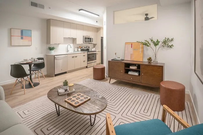 Modern open-concept living area featuring a sleek kitchen, stylish dining table, and cozy seating with chic decor.