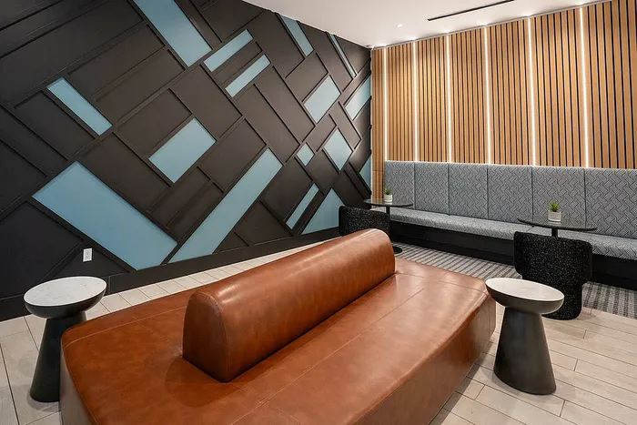 Modern lounge area with geometric wall design, cozy seating, and chic accent tables, perfect for relaxation and social gatherings.