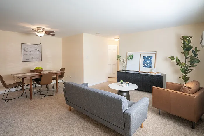 Bright and inviting living space with modern furniture, featuring a cozy sofa, chic armchair, stylish dining table, and elegant decor.
