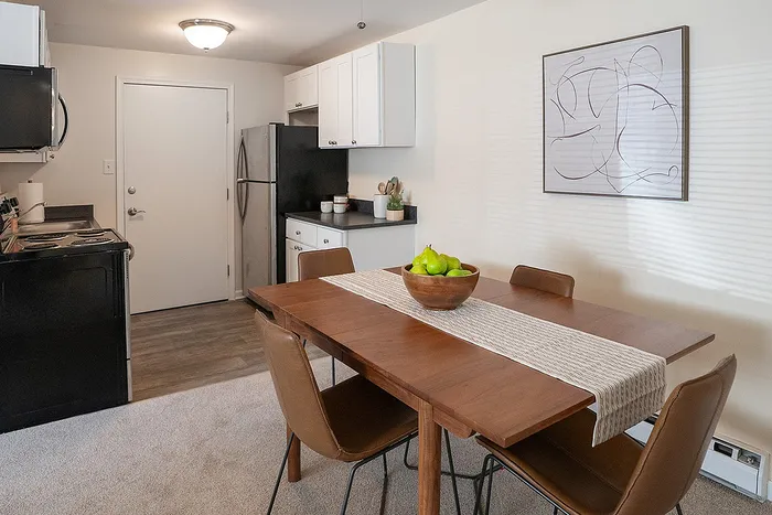 Inviting dining area with elegant wooden table, stylish chairs, and a modern kitchen featuring stainless steel appliances.