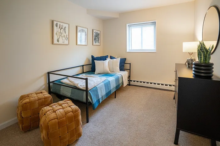 Cozy bedroom with stylish decor, featuring a modern daybed, plush pillows, and unique woven ottomans.