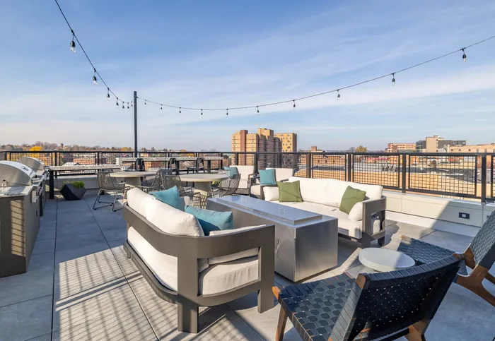 Stunning rooftop terrace with modern seating, string lights, and expansive city views.