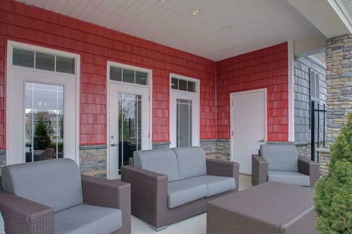 Charming outdoor seating area with elegant gray wicker furniture and vibrant red siding, perfect for relaxation and social gatherings.