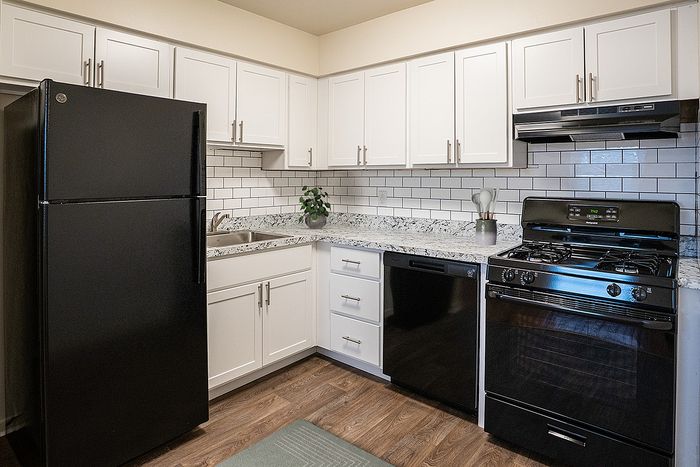 Elegant kitchen featuring sleek black appliances, white cabinets, and granite countertops, with a modern tile backsplash.