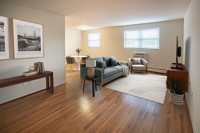 Chic apartment living room with stylish decor, hardwood floors, and abundant natural light, adjacent to a cozy dining area.