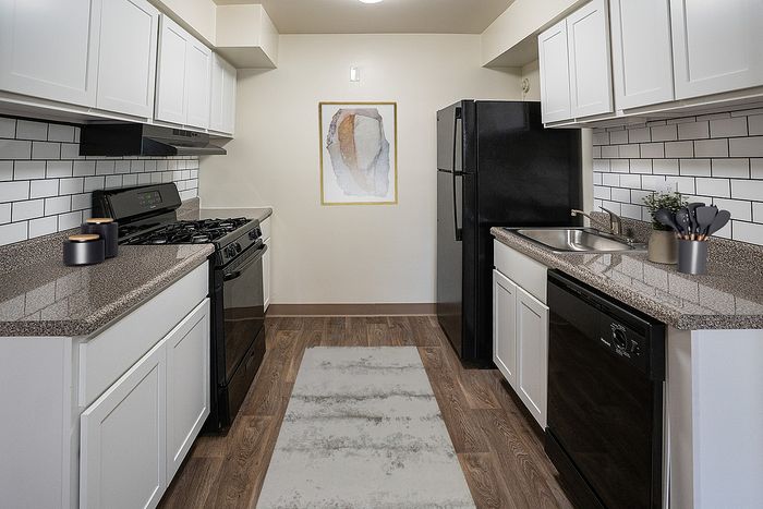 Chic galley kitchen with modern appliances, granite countertops, and stylish white cabinetry, perfect for culinary enthusiasts.