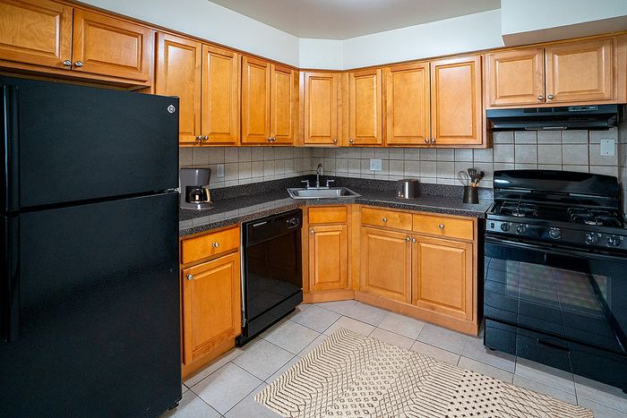 Modern kitchen with warm wooden cabinets, sleek black appliances, and stylish tile backsplash.