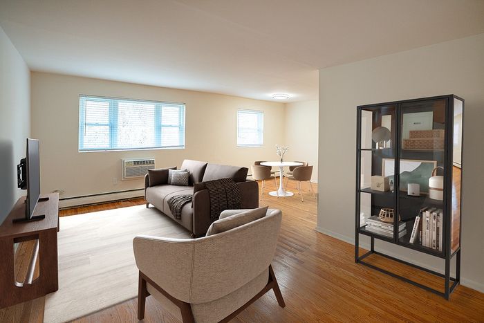 Bright apartment living area with stylish furnishings, featuring a cozy sofa, modern armchair, and airy dining nook near large windows.