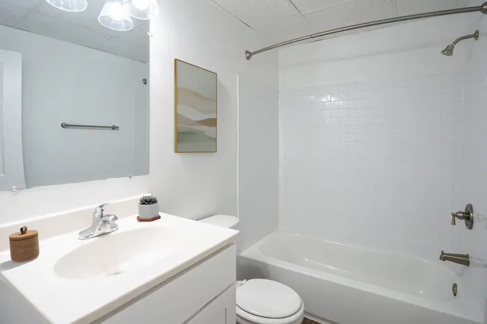 Bright and modern bathroom with sleek white tiles, elegant fixtures, and minimalist decor.