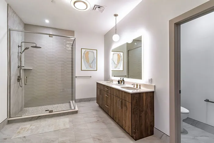 Luxurious modern bathroom featuring a spacious glass shower, elegant double vanity, and ambient lighting.