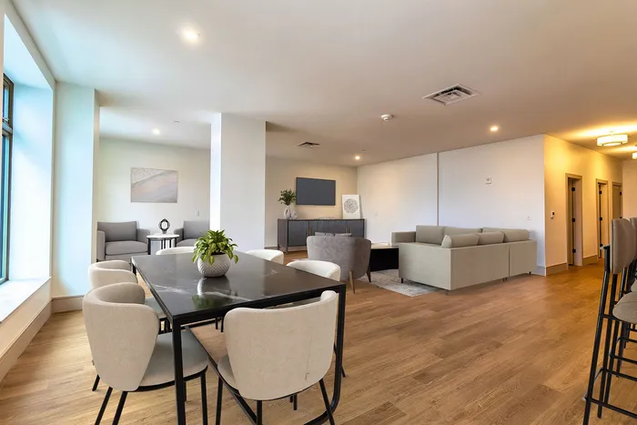 Modern open-plan living area with elegant dining space, cozy seating, and stylish decor, featuring large windows and warm wooden flooring.