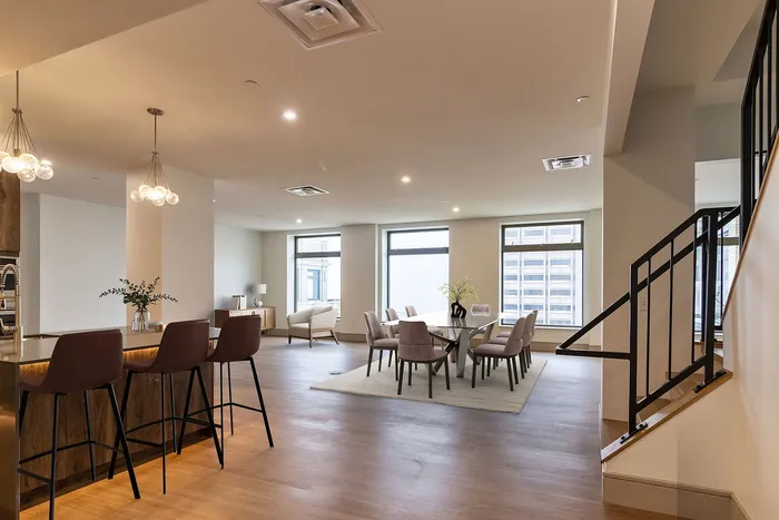 Luxurious open-concept apartment featuring a stylish kitchen bar, elegant dining area, and natural light-filled living space with city views.