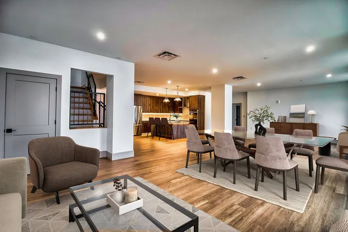 Elegant open-concept living space featuring a modern kitchen with island seating, a cozy dining area, and a spacious living room with stylish furnishings.