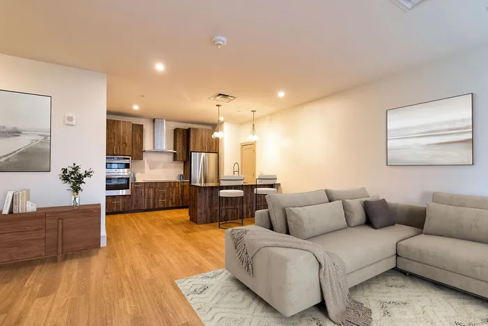 Contemporary open-plan living area with cozy sectional sofa, sleek kitchen featuring modern appliances, and stylish lighting.