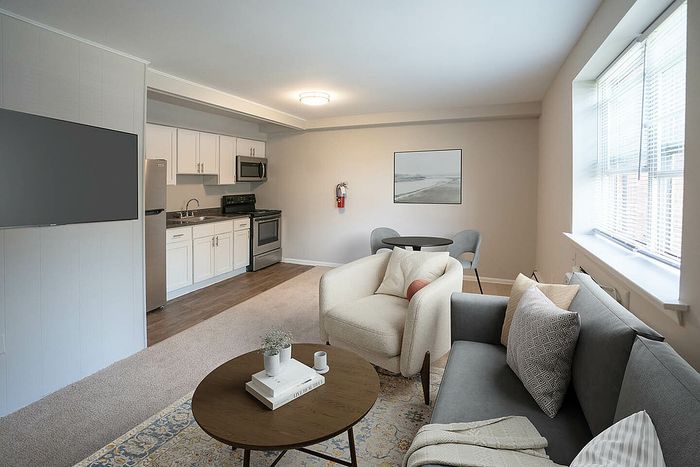 Bright and inviting open-concept living room with a modern kitchen, cozy seating area, and large windows offering natural light.
