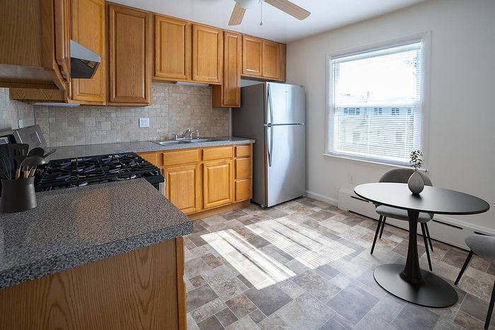 Bright and welcoming kitchen featuring modern stainless steel appliances, elegant wood cabinetry, and a cozy dining nook with a stylish round table and chairs.