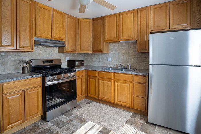 Charming kitchen with warm wooden cabinets, modern appliances, and stylish tile backsplash.