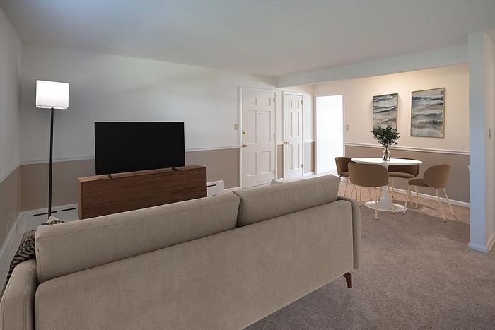 Elegant living room with a cozy beige sofa, modern TV setup, and chic dining area featuring a round table with stylish chairs, perfect for comfortable urban living.