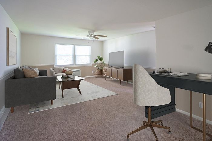 Inviting living room with plush carpet, modern furniture, and large windows for natural light.