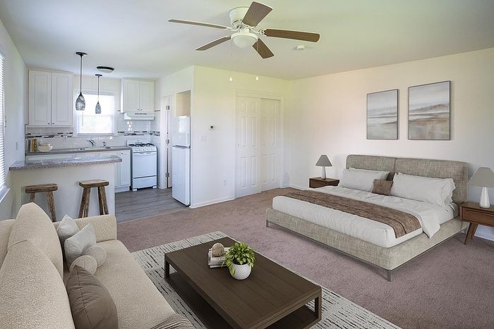 Modern studio apartment with an open layout featuring a cozy living area, stylish kitchen, and a comfortable bed. Natural light enhances the sleek design and calming ambiance.