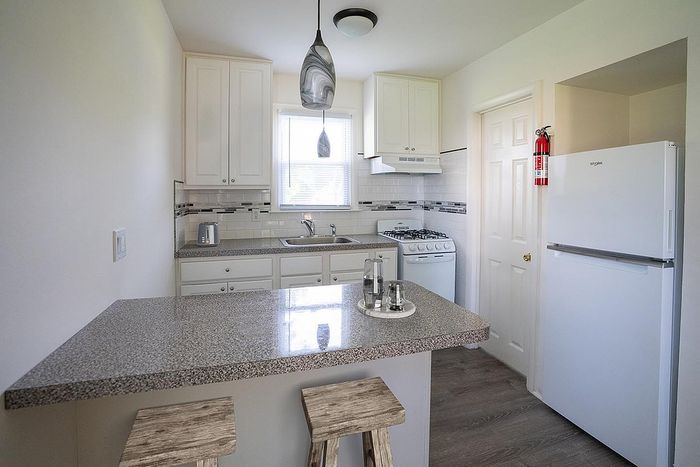 Bright, modern kitchen with sleek countertops, cozy breakfast bar, and stylish lighting.
