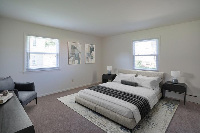 Bright and spacious bedroom with modern decor, featuring large windows, elegant artwork, and a cozy double bed.